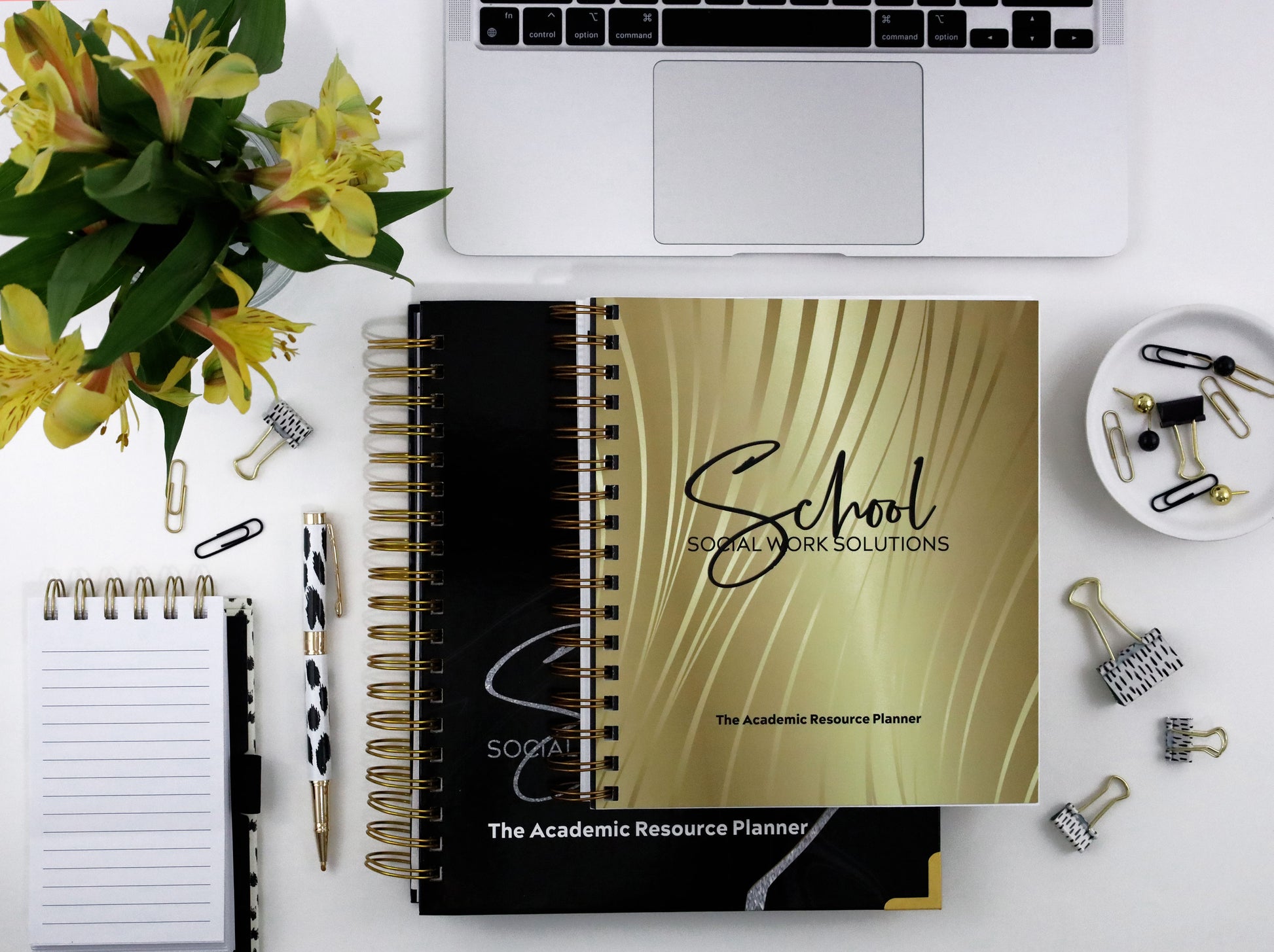  planner on a desk with laptop, flowers, and office supplies