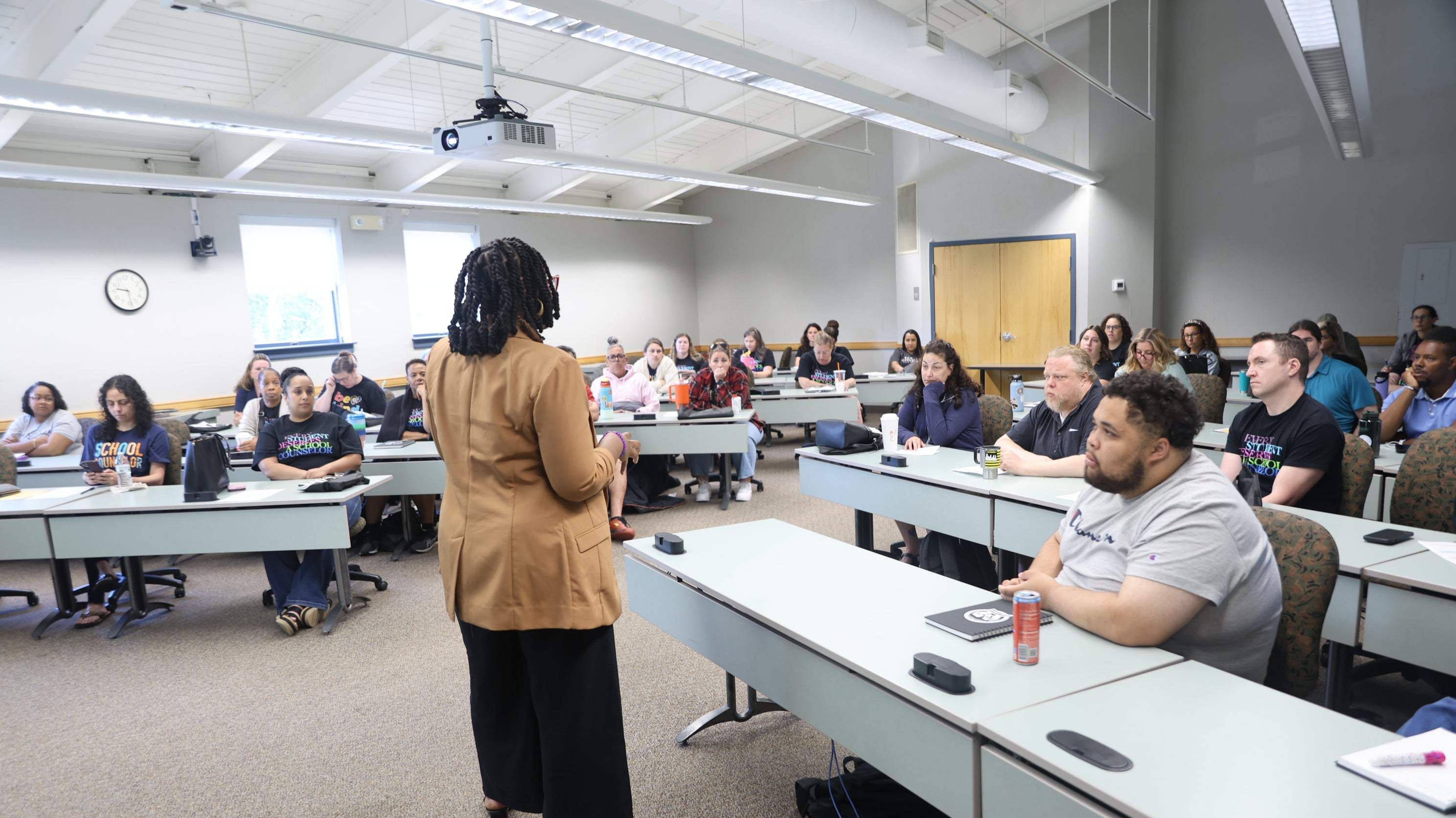 Person giving a lecture in a classroom with students seated at desks.